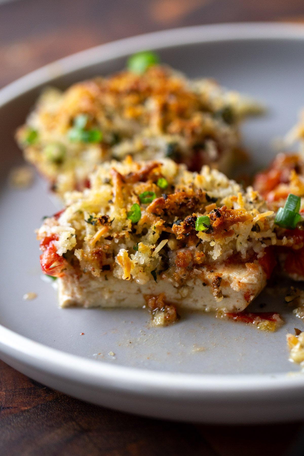 baked vegan caprese stacks on a plate with a bite taken out