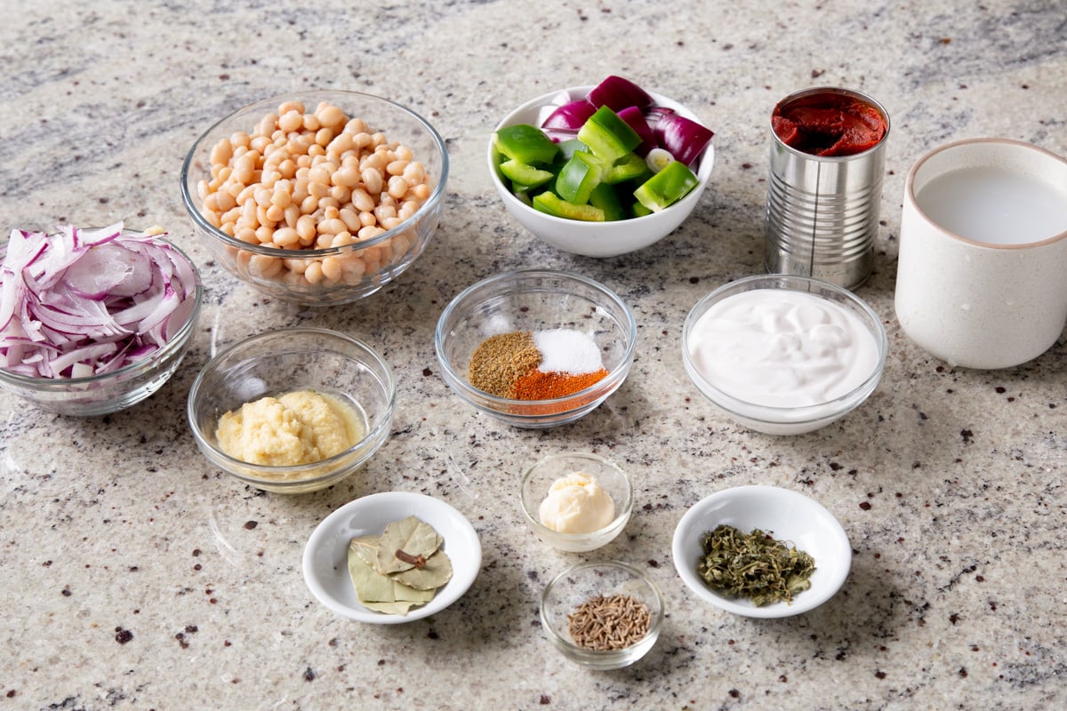 beans, onions, and other vegan chicken do pyaza ingredients in bowls on the kitchen counter