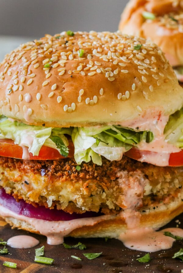 two crispy vegan chicken sandwiches on a wooden cutting board