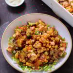 gochujang tofu and veggies in bowl over lettuce, next to the baking dish