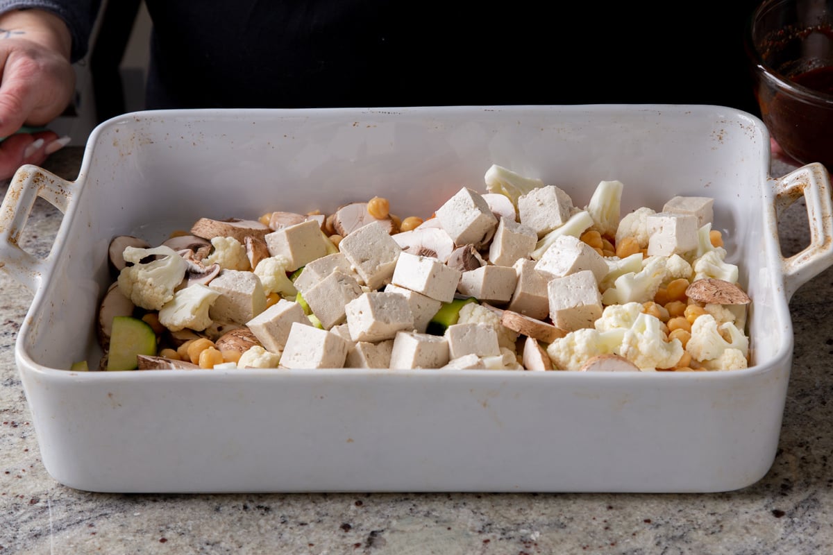 adding tofu to the pan of veggies and chickpeas