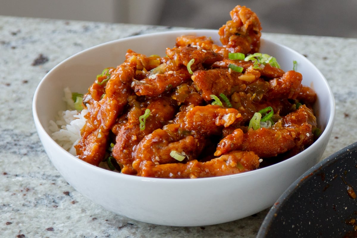 crispy Indo Chinese chicken in a bowl with rice and green onions