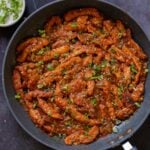crispy Indo Chinese chicken in the pan with rice and green onions