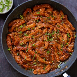 crispy Indo Chinese chicken in the pan with rice and green onions
