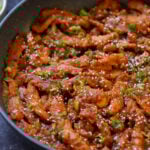 close-up of crispy Indo Chinese chicken in the pan with rice and green onions