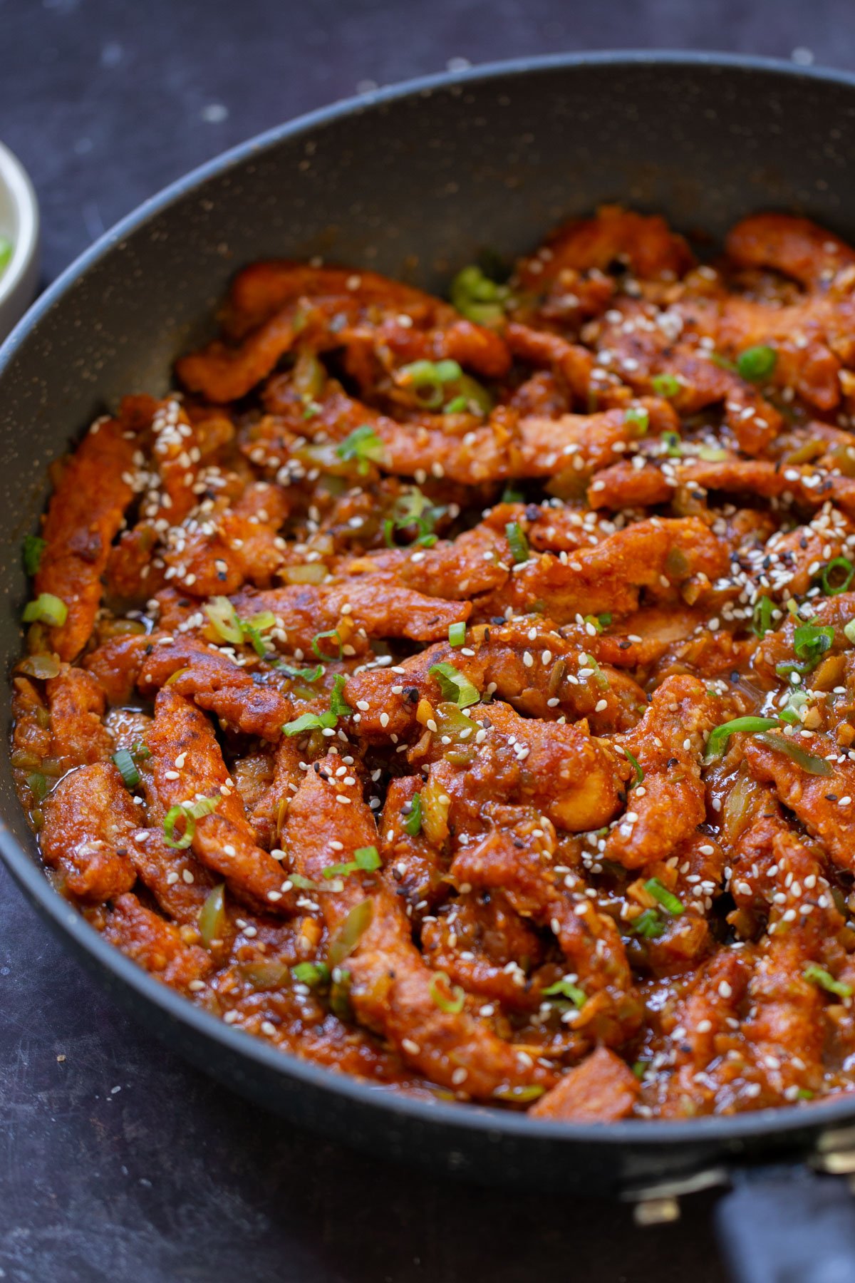 close-up of crispy Indo Chinese chicken in the pan with rice and green onions