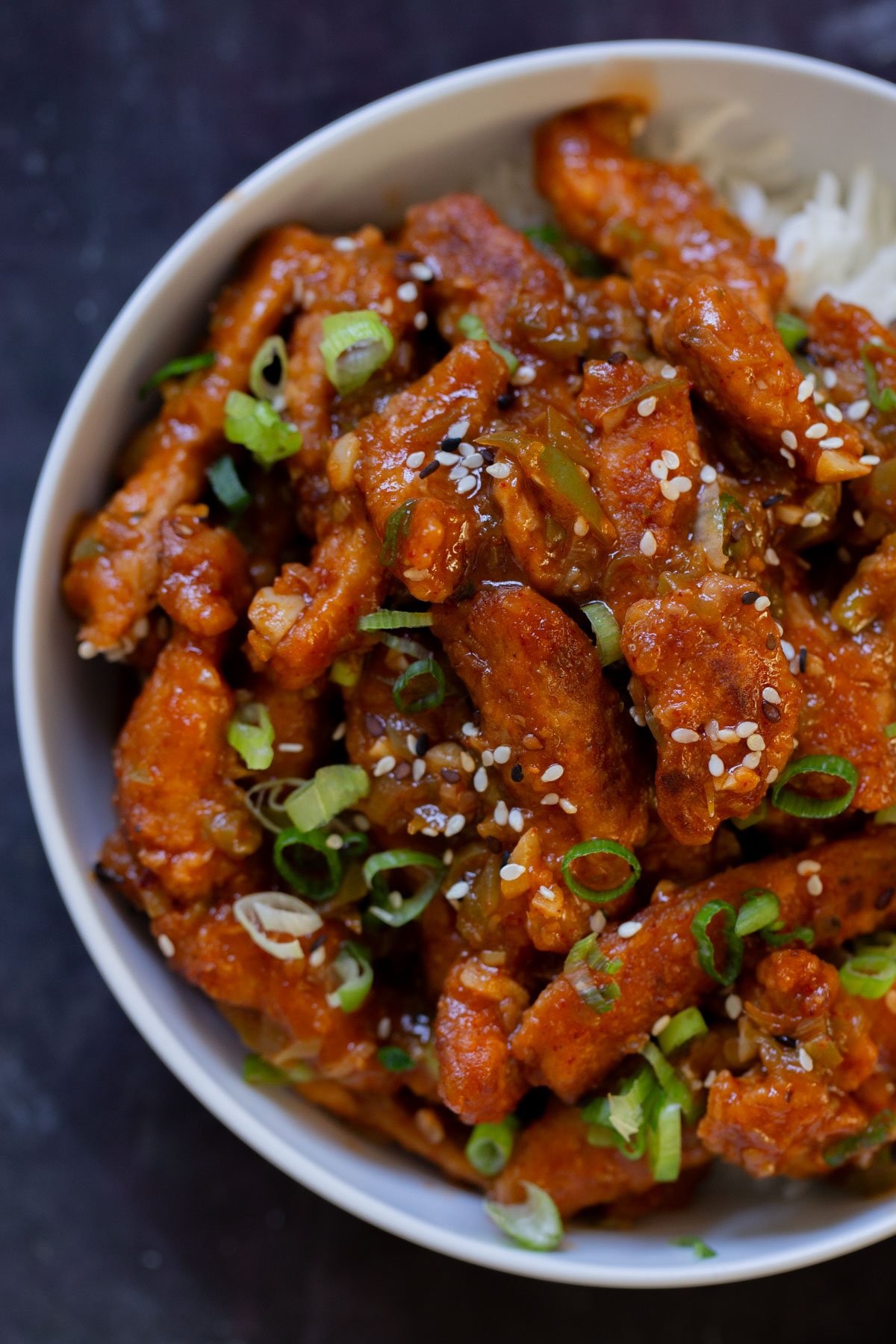 overhead close-up of crispy Indo Chinese chicken in a bowl with rice and green onions