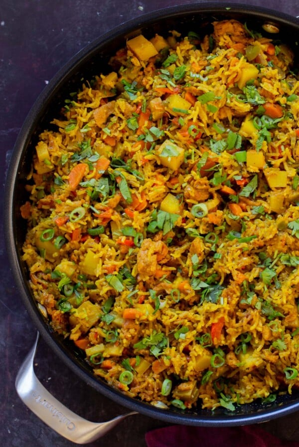 Jamaican curry rice in the pan with cilantro and green onions