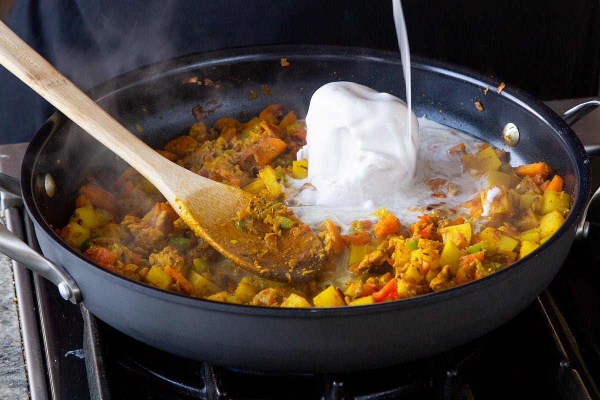 adding coconut milk and water to the pan