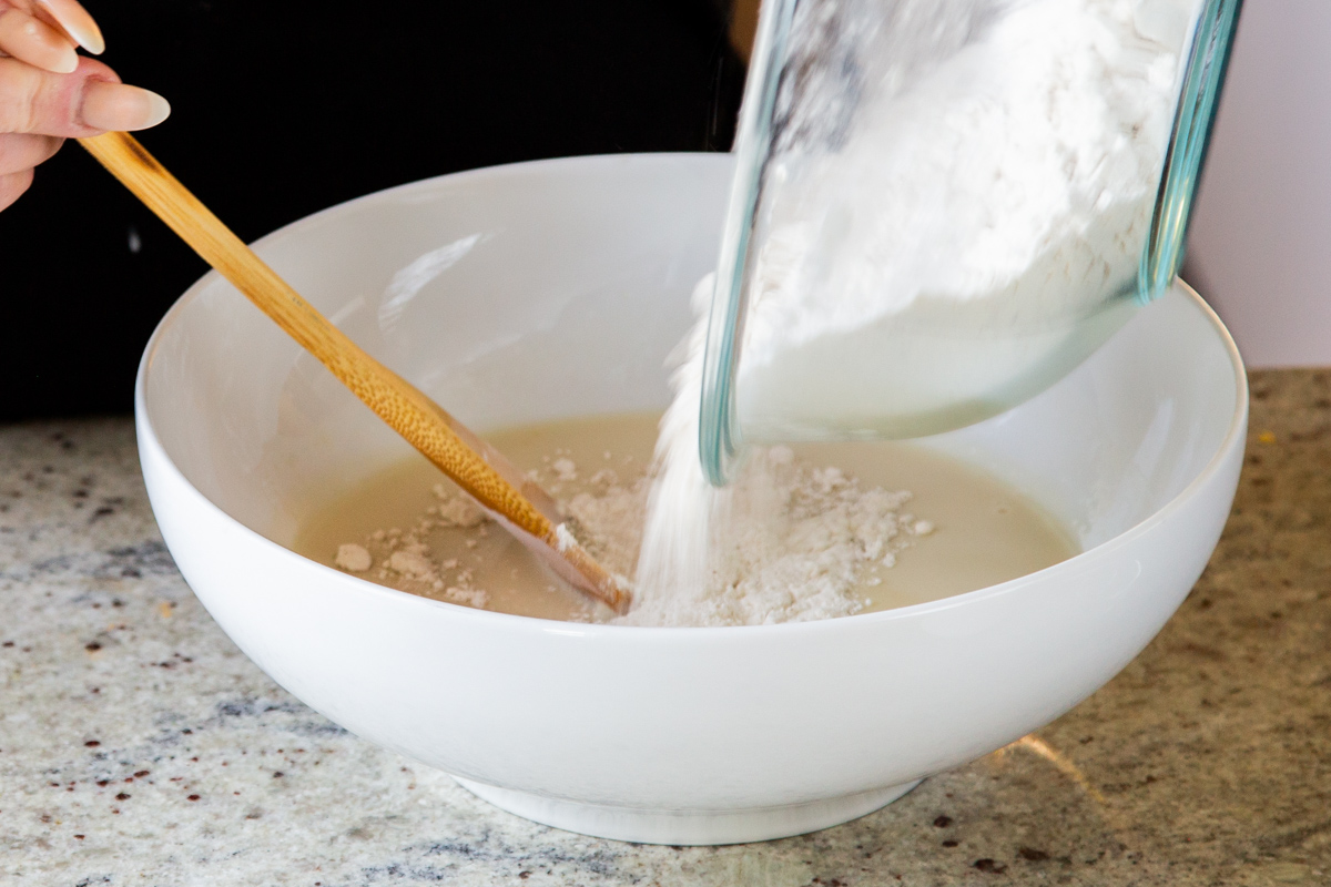 adding dry ingredients to the wet in the mixing bowl