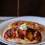 drizzling maple syrup onto a plate of peach upside-down pancakes