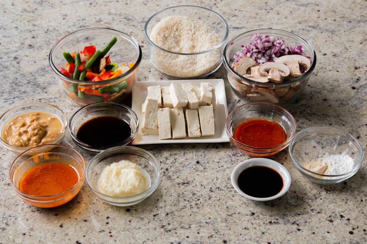 gochujang, rice, peanut butter, and other ingredients in bowls on a kitchen counter
