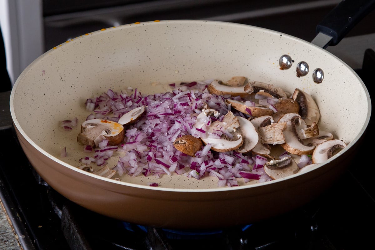 adding onion and mushrooms to the pan
