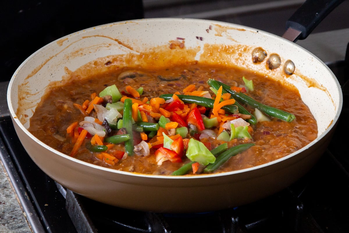 adding veggies to the peanut gochujang sauce