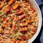 close-up of peanut gochujang rice topped with tofu and green onions in a skillet