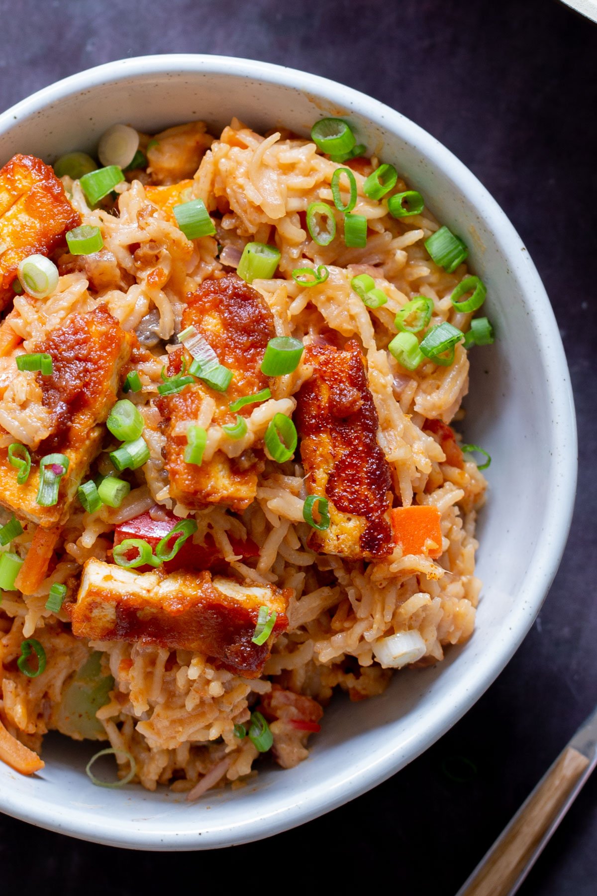close-up of peanut gochujang rice topped with tofu and green onions in a bowl