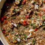 close-up of caramelized onion beans in the pan topped with charred cauliflower, tomato, and herbs
