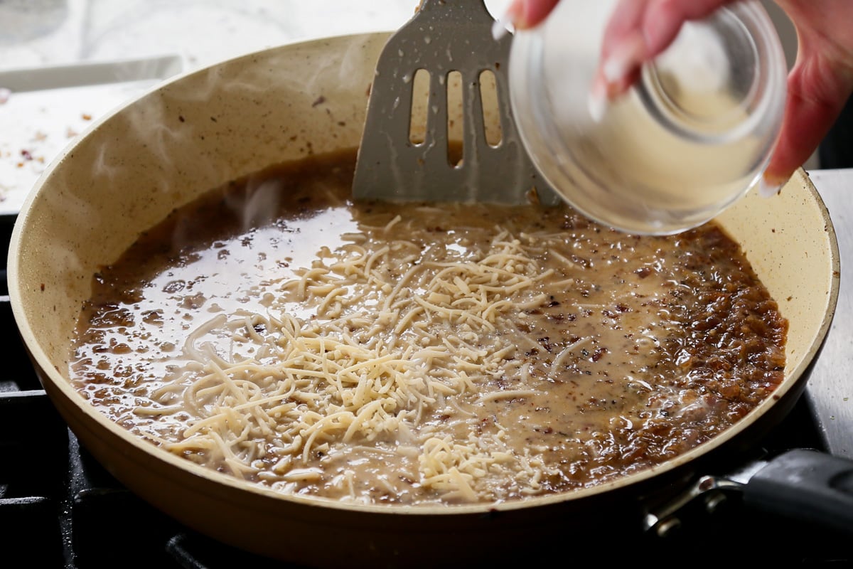 adding vegan parmesan to the pan