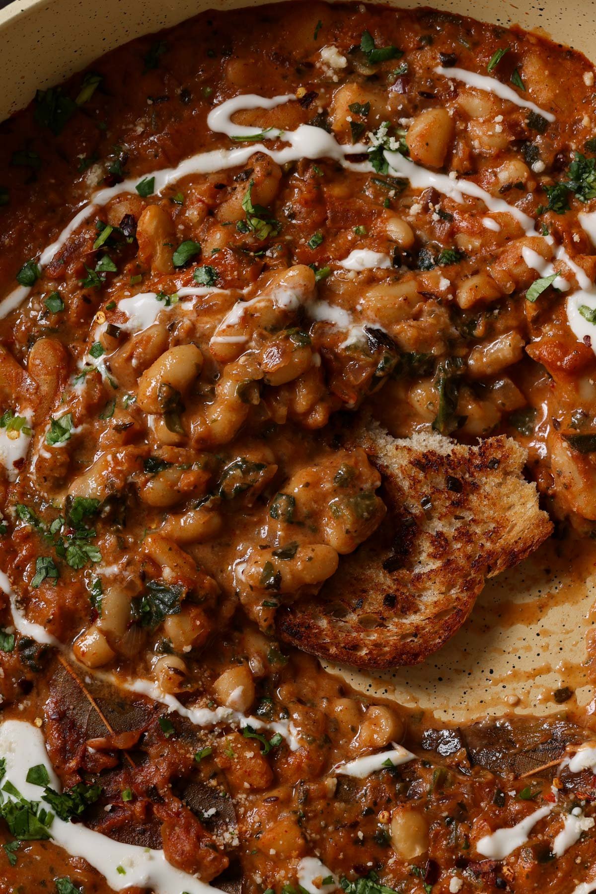 close-up of dipping sourdough into Dhaba chicken white beans