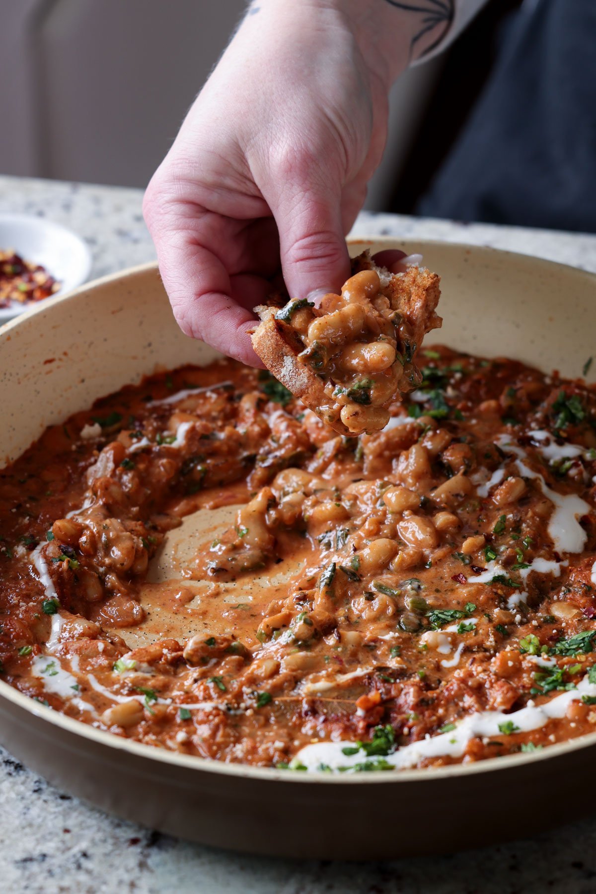 dipping sourdough into Dhaba chicken white beans
