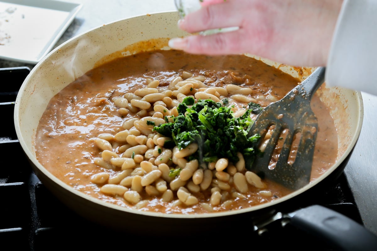 adding white beans and spinach to the pan