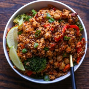 quinoa chickpea casserole in a bowl with lime wedge and green onion