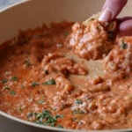 dipping sourdough into rosé sauce beans in the pan