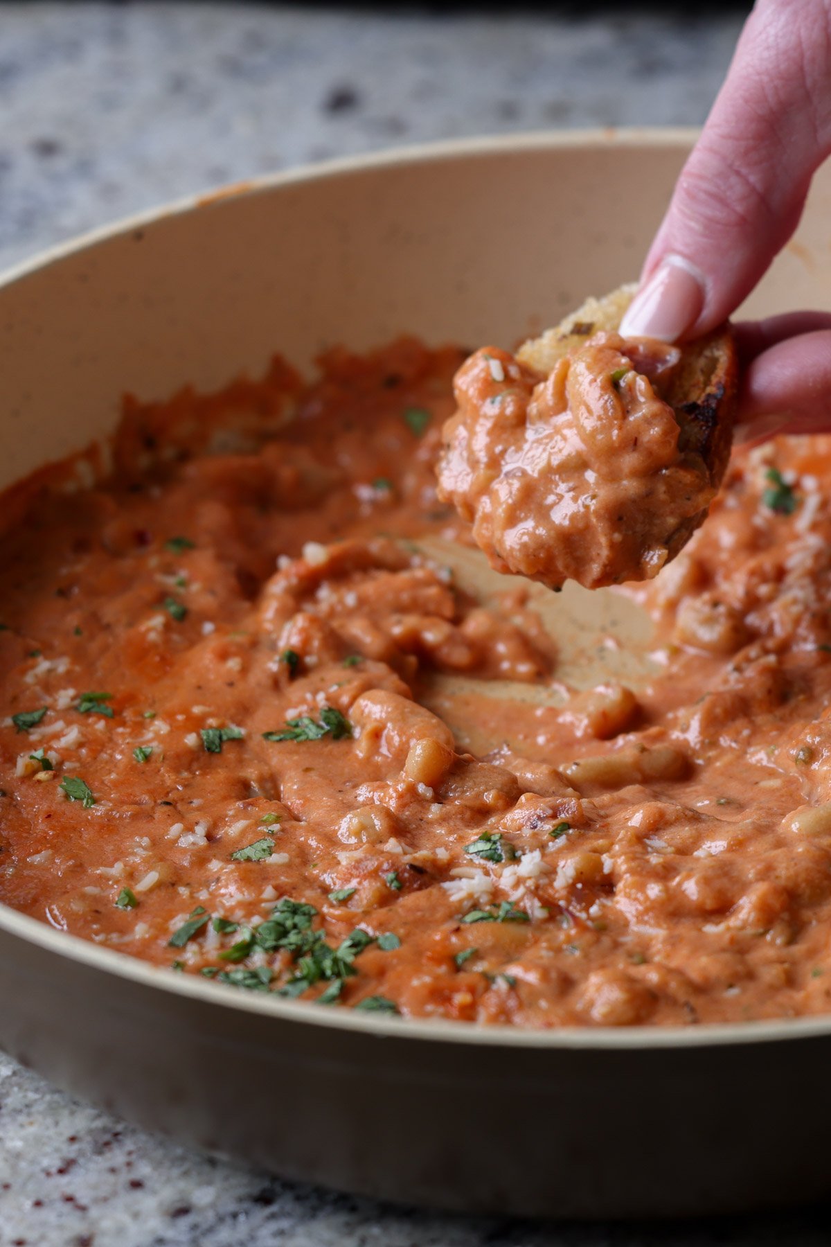 dipping sourdough into rosé sauce beans in the pan