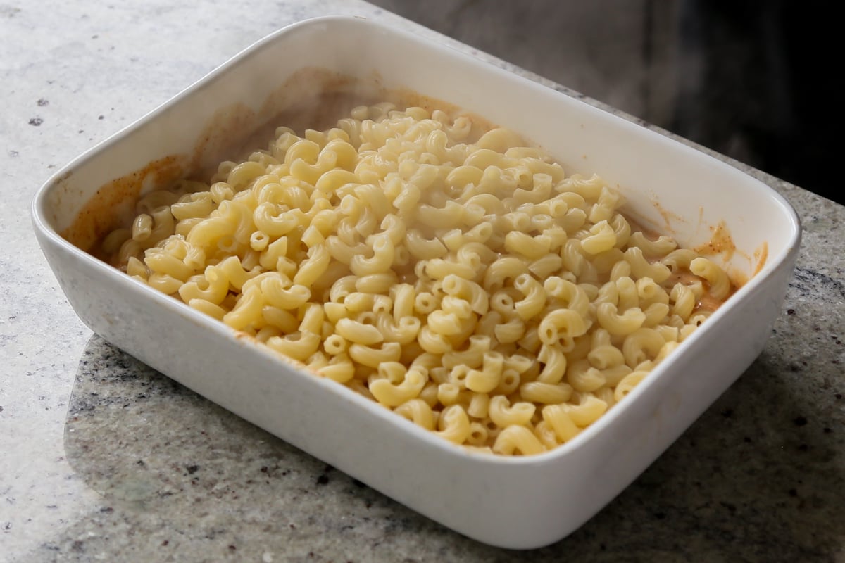 adding pasta to the pan of vegan smoky cheese sauce