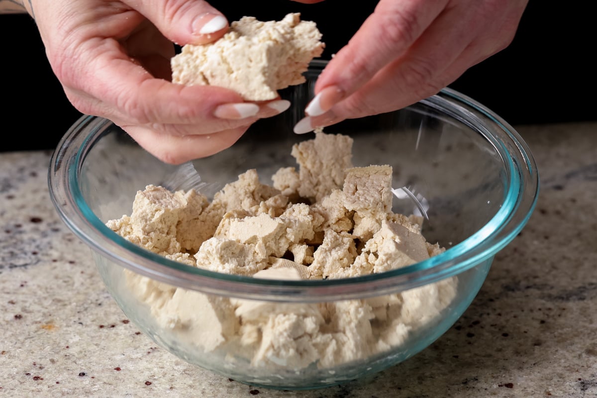 tearing the tofu into bite-sized pieces