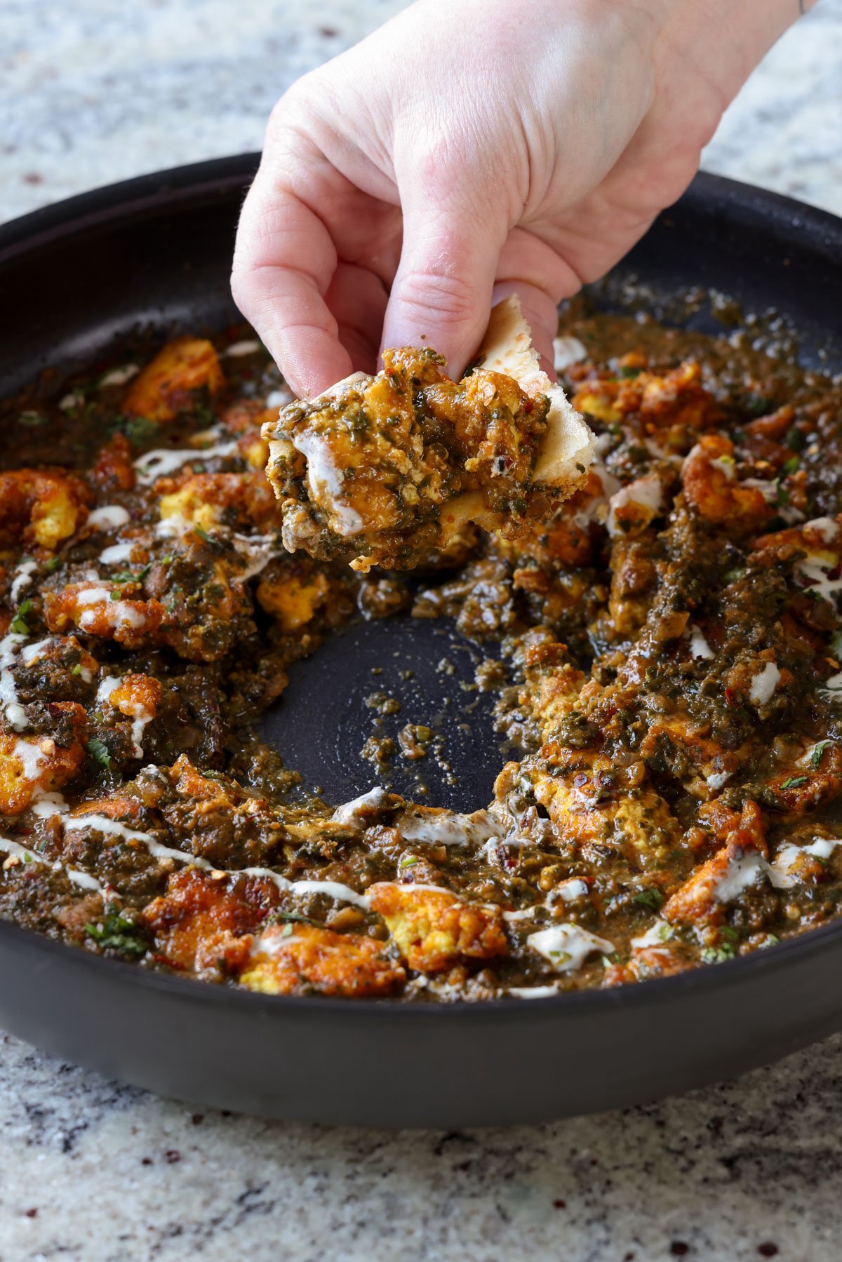 dipping flatbread into chicken saagwala