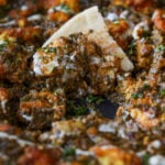close-up of a piece of flatbread in the pan of chicken saagwala