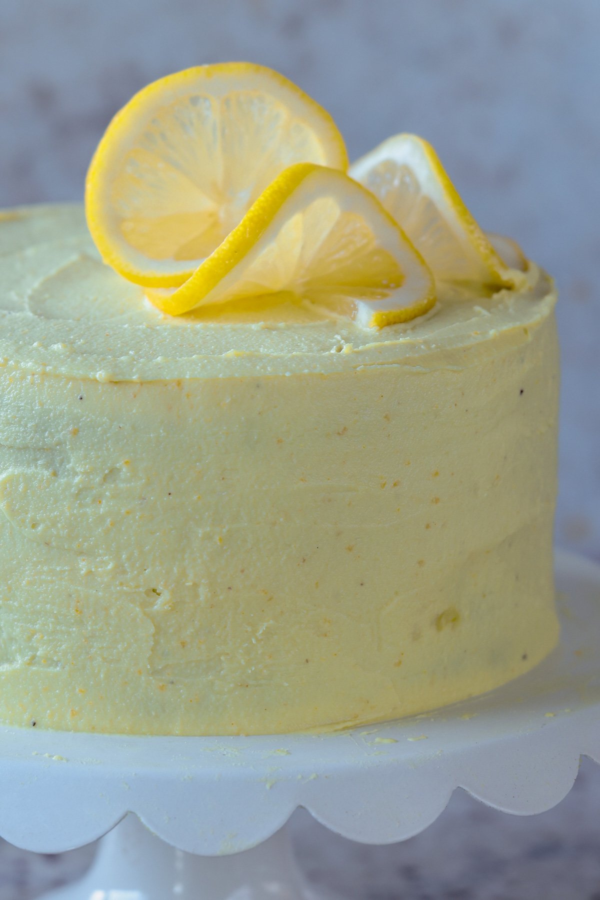 close-up of vegan lemon cake on the serving tray after frosting and topping with lemon slices