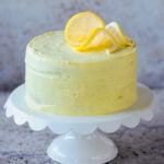 vegan lemon cake on the serving tray after frosting and topping with lemon slices