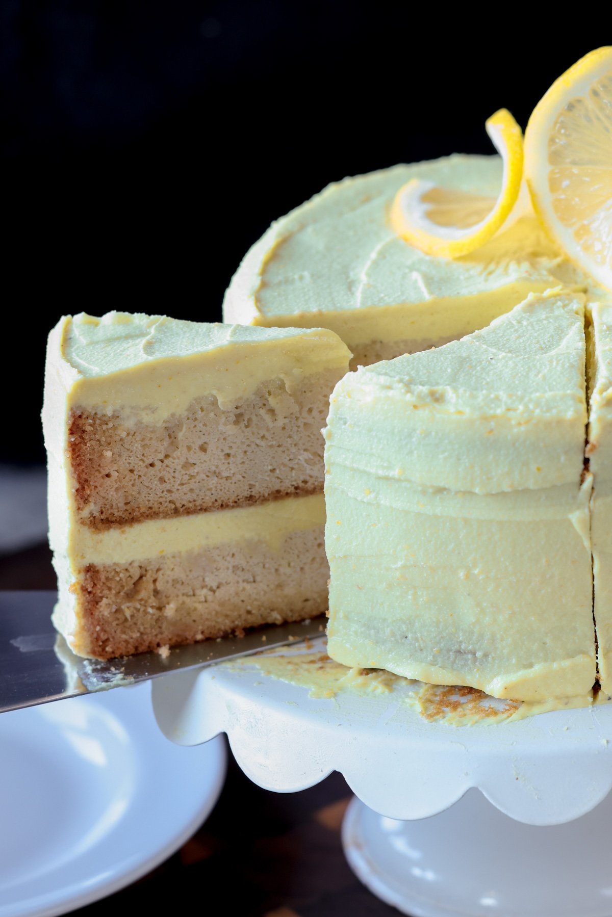 removing a slice of vegan lemon cake from the cake stand