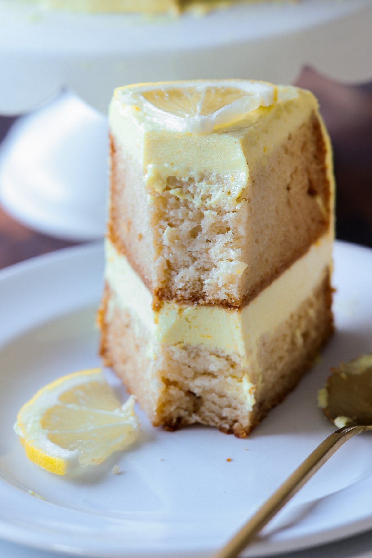 vegan lemon cake on the cake stand next to slices of the cake