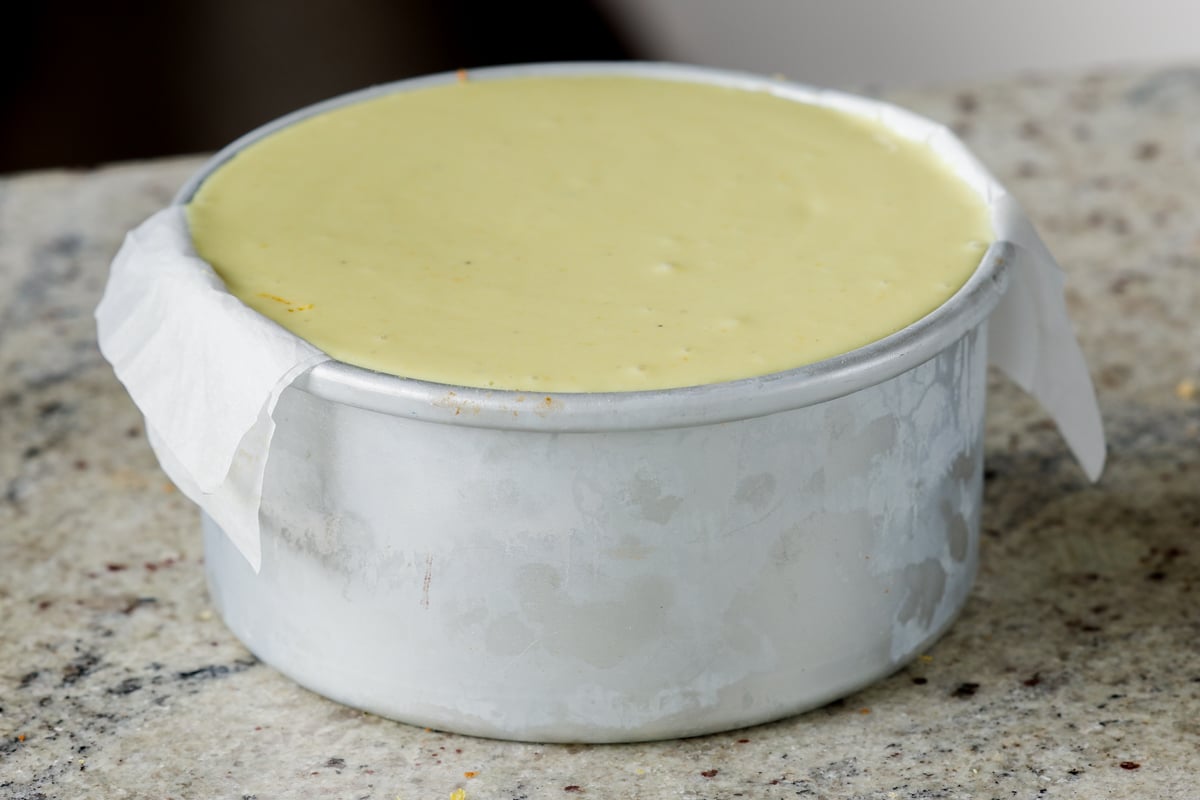 adding the second layer of frosting to the cakes in the pan