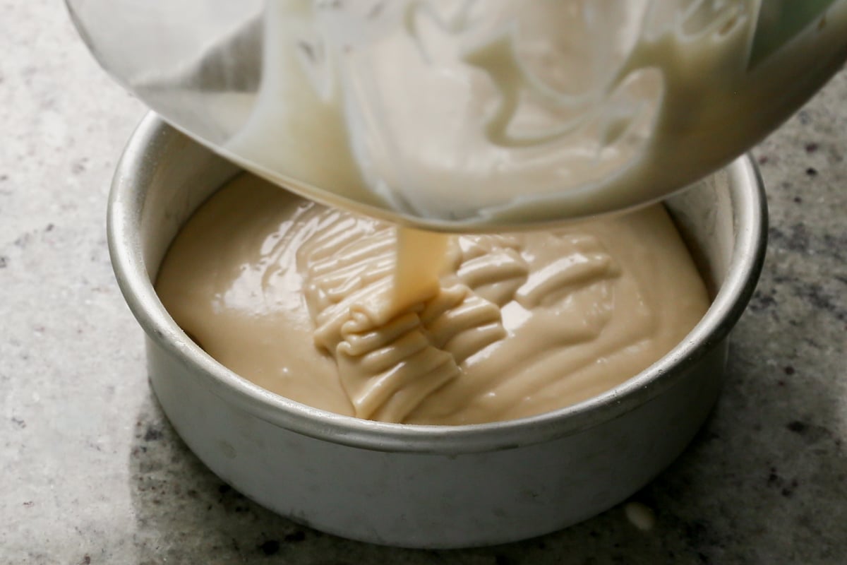 adding half of the cake batter to the pan