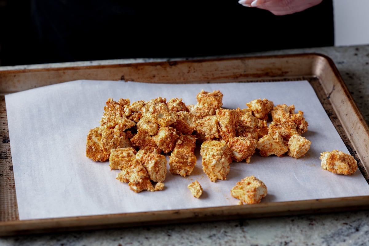 tofu coated in cornstarch and spices on the baking sheet before baking