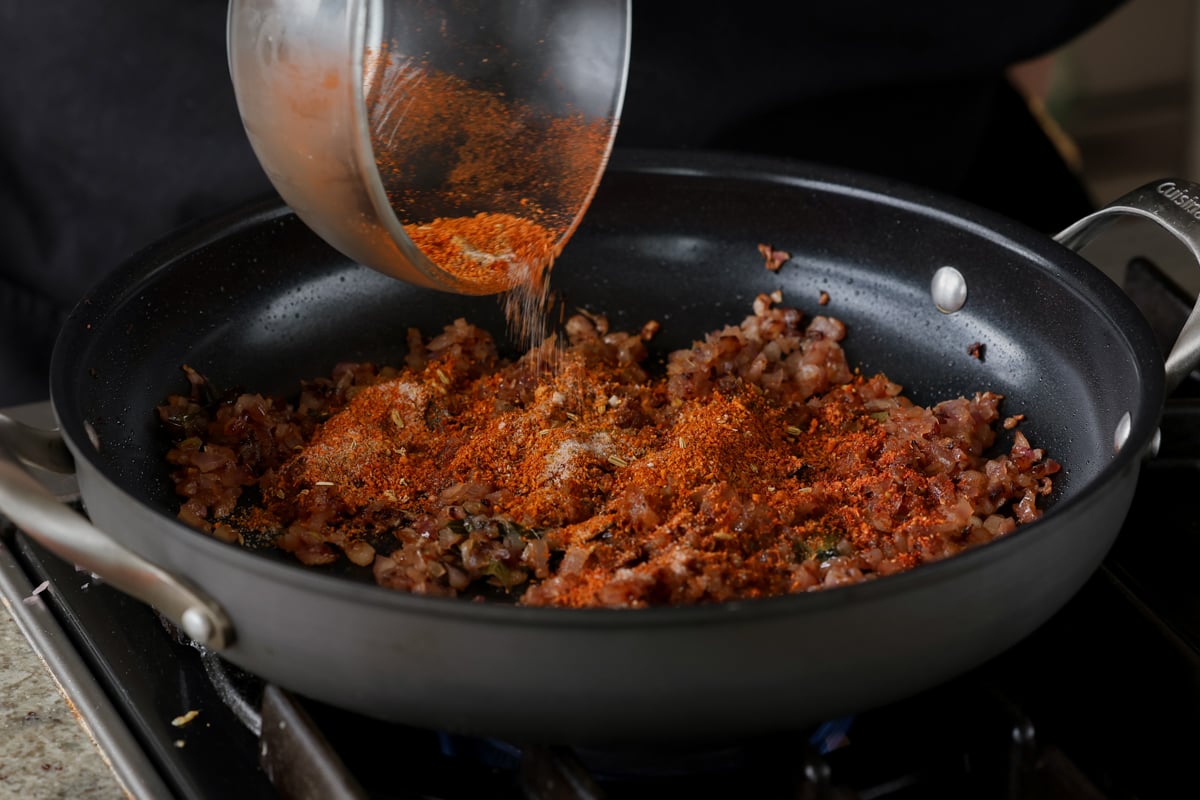 adding the remaining spice mix to the cooked onions in the pan