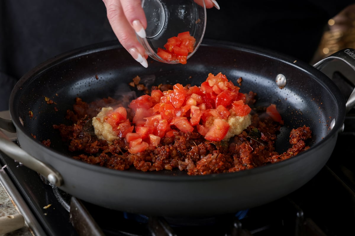 adding tomatoes to the pan