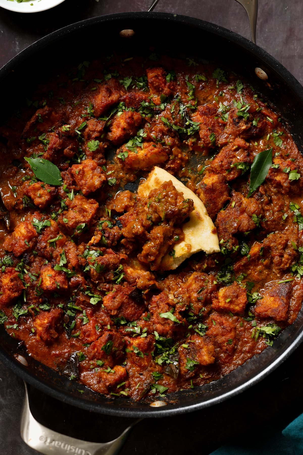 Madurai Chicken Curry in the pan with a piece of flatbread in it