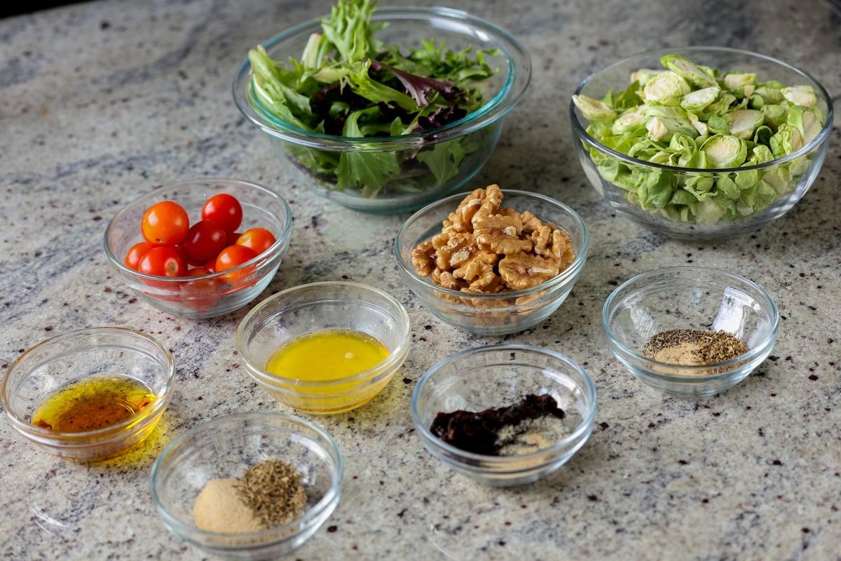 Brussels sprouts salad ingredients in bowls on a kitchen counter