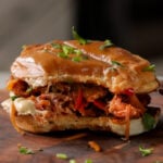 vegan cheesesteak sandwich on a cutting board with a bite taken out