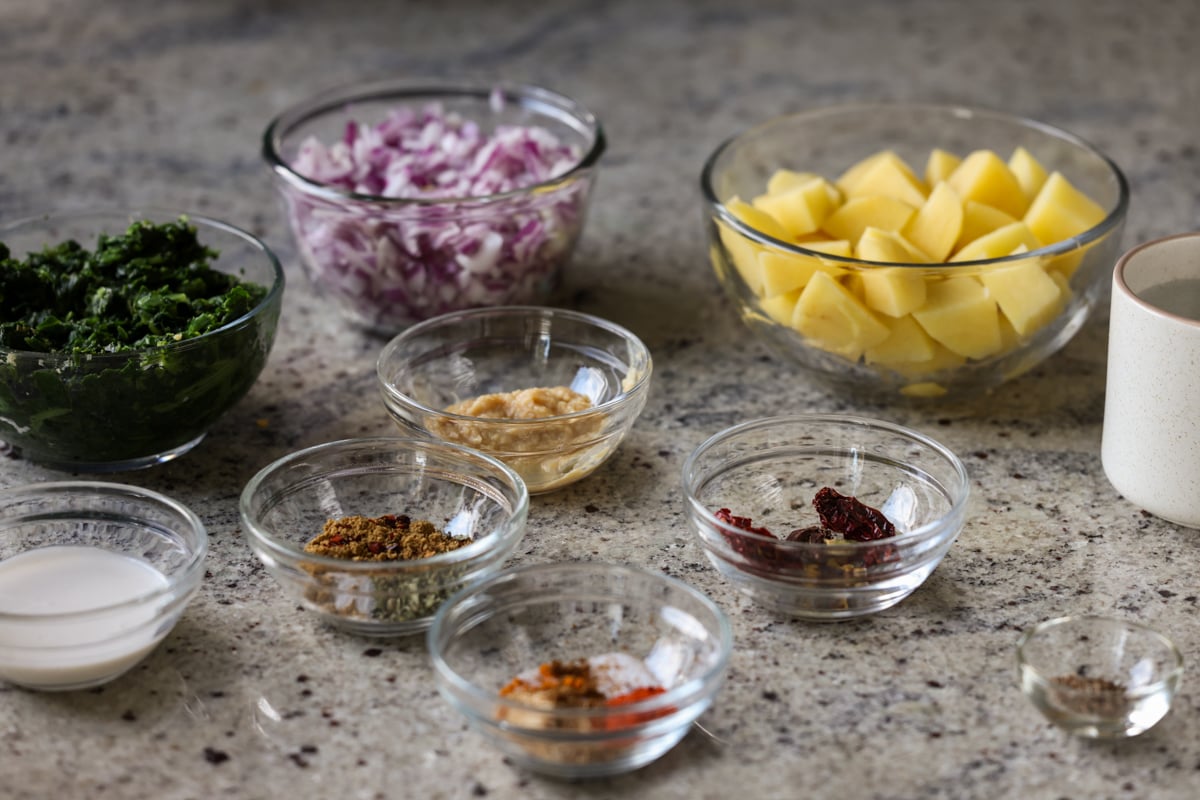 spinach, potatoes, and other saag aloo ingredients on the kitchen counter