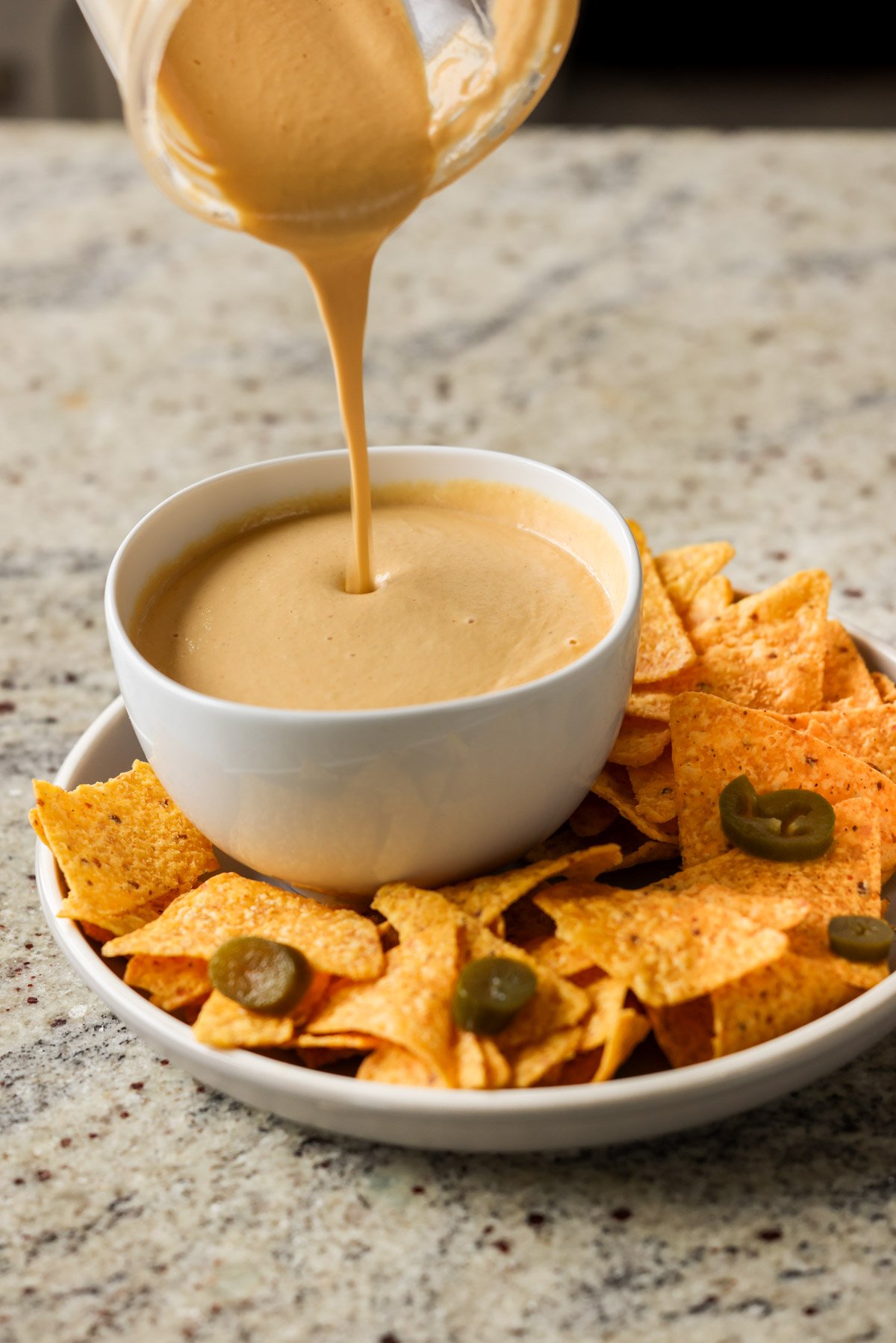 pouring cashew nacho cheese into a serving bowl