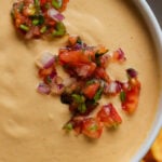 close-up of cashew nacho cheese in a serving bowl topped with salsa