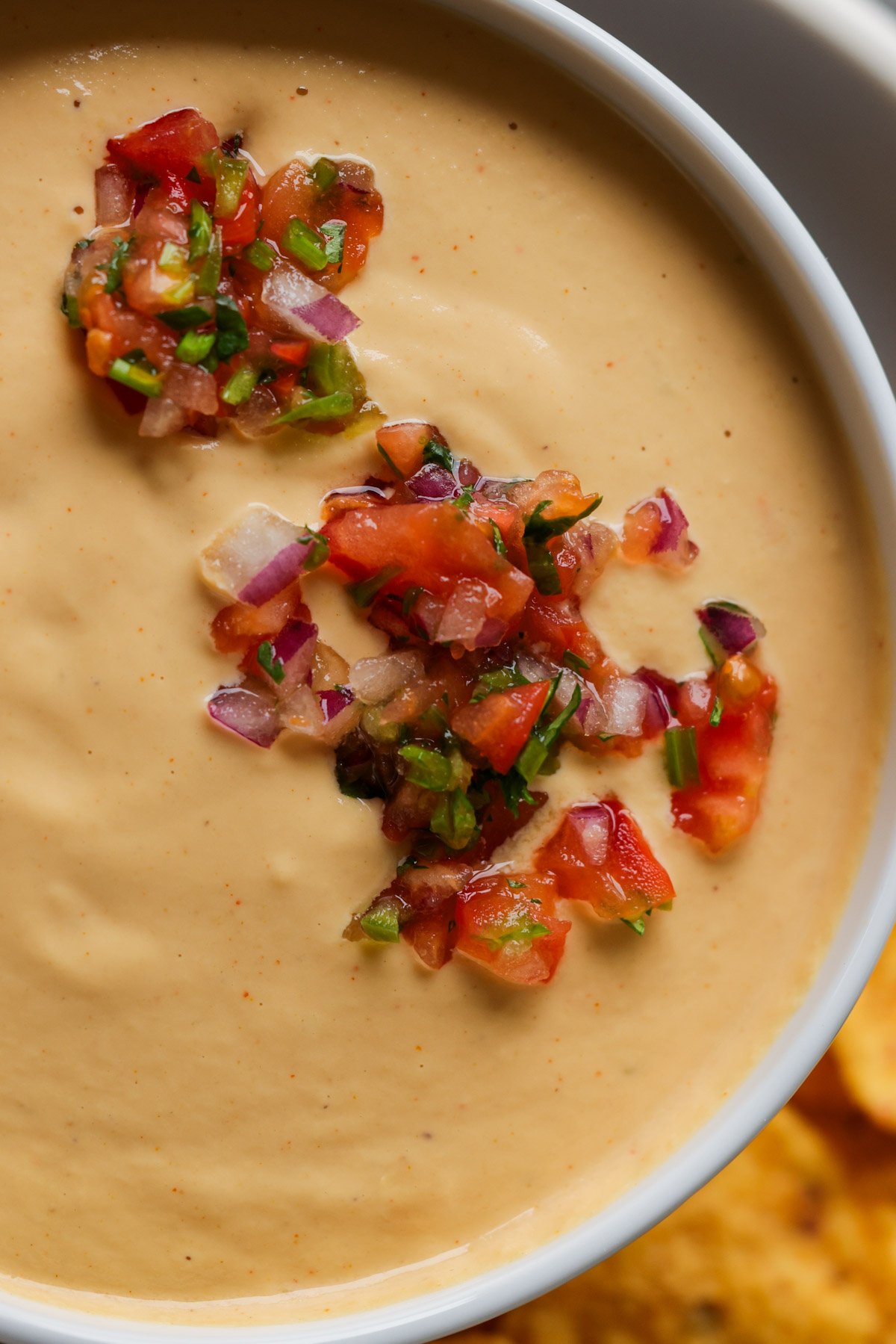 close-up of cashew nacho cheese in a serving bowl topped with salsa