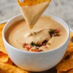 dipping a chip into cashew nacho cheese sauce