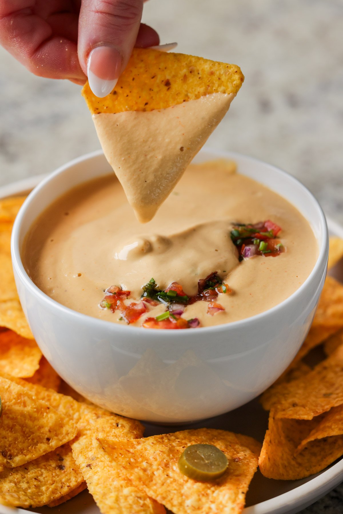 dipping a chip into cashew nacho cheese sauce